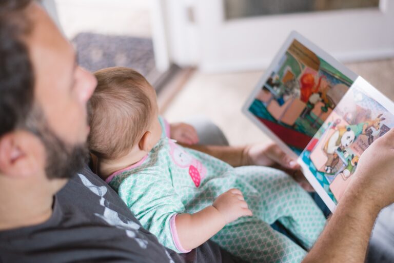 Dad with a baby, reading a story book together.